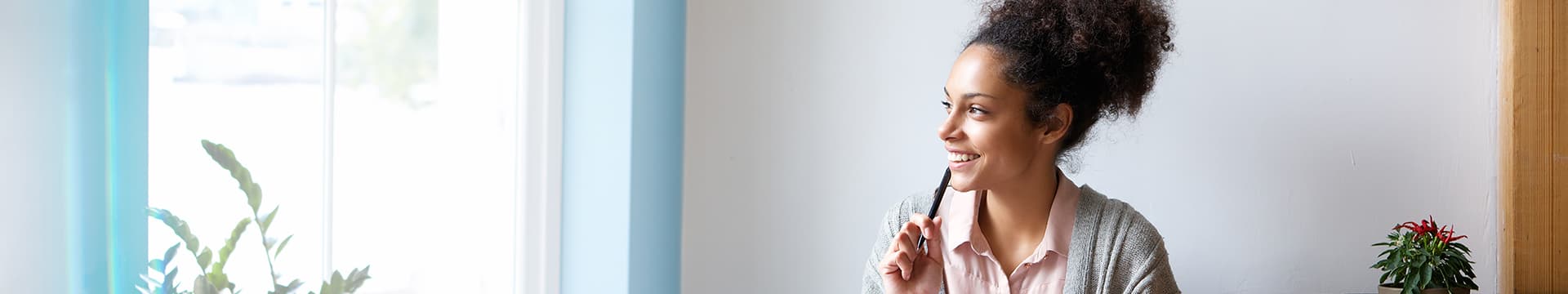 Young woman smiles in thought while looking out window