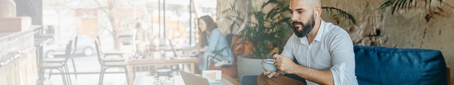 Man watching a video on a laptop while sitting in a coffee shop