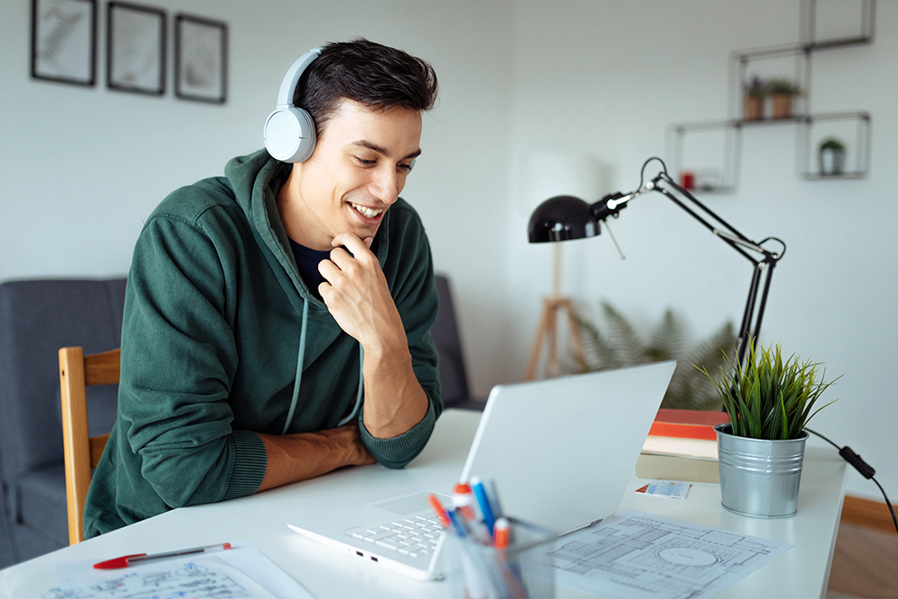 young man smiling at laptop studying