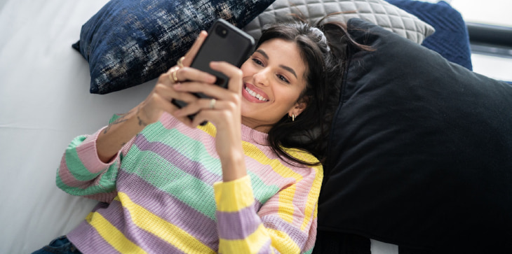 Lady laying down on the floor while checking her net worth on mobile