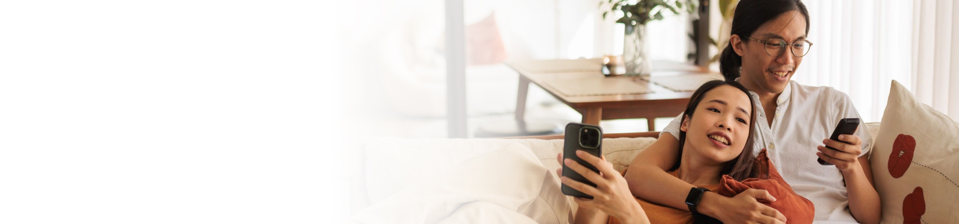Couple relaxing on couch with cell phones in hand